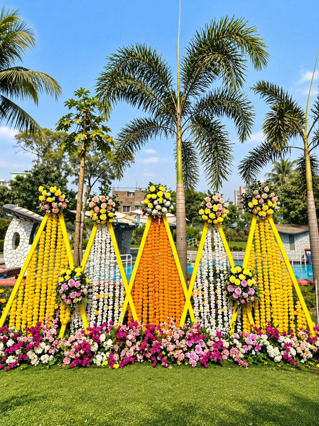 Palm trees against a blue sky with rose bouquets on stands at an outdoor wedding venue