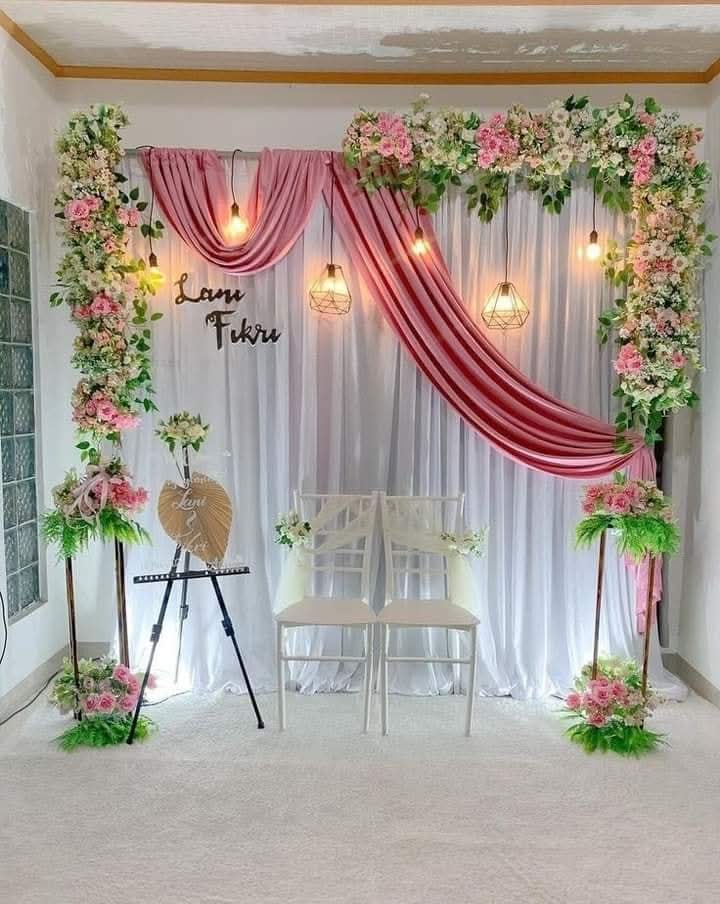 Indoor engagement stage decorated with pink drapes, flower garlands and hanging lights